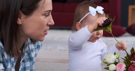 Mother and cute little daughter arranging rose flowers together at home