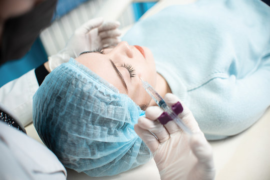 Woman doctor conducts a medical procedure to clean the face of a young girl. Acne treatment. Doctor and patient