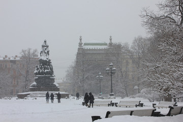 Ekaterininsky garden at Ostrovsky square with monument to empress Catherine II on winter day in St. Petersburg, Russia. Snowstorm at city park view with snow covered streets and misty sky background 