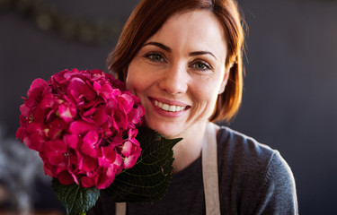A portrait of young creative woman in a flower shop. A startup of florist business.