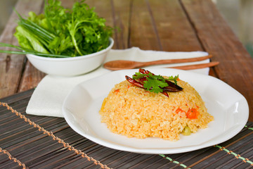 Tomato fried with dried chili rice on white dish and wooden table for served in cafe and restaurant.  