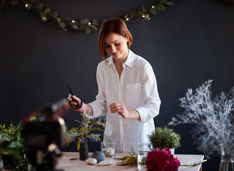 Young creative woman vlogger in a flower shop. A startup of florist business.