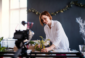 Young creative woman vlogger in a flower shop. A startup of florist business.