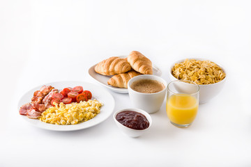 Breakfast with scrambled eggs, bacon, tomatoes,coffee,orange juice ,croissant and corn flakes isolated on white background. 