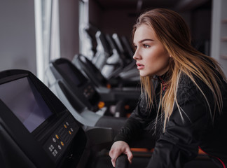 A side view of young girl or woman doing cardio workout in a gym.