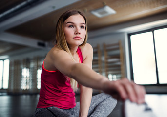 A portrait of young girl or woman doing exercise in a gym.