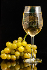 wine glass with wine and a bunch of grapes against a black background