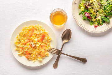 Pasta and wine, Italian meal. Farfalle with salmon and cream sauce, shot from above with a glass of white wine, mesclun leaves salad, and copyspace