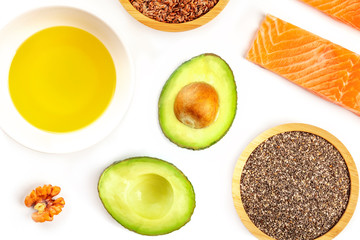 A closeup photo of the ingredients of a healthy omega-3 diet. Raw salmon, avocado, nuts, chia and flax seeds, shot from above on a white background