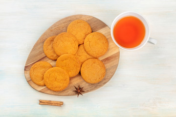 Gingersnaps, shot from above with a cinnamon stick, an anise star, a cup of tea, and a place for text