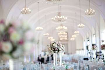 Big wedding hall well decorated in pastel colors - chandeliers on vaulting.