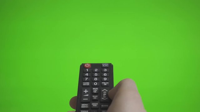 Male hand with TV remote pressing channels over green screen. Place for your advertisement.