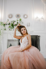 Beautiful girl in a pink dress sitting in an armchair