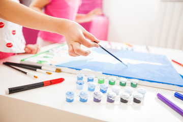 little artist hands with brush painting on canvas