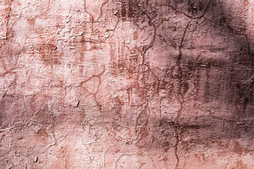 Dirty pink wall with peeling paint and cracks