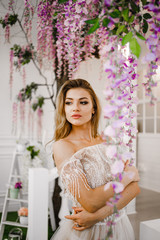 A magnificent bride in a white dress posing in the spring hall