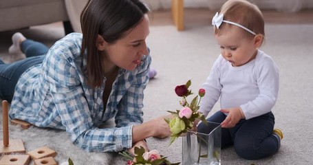 Happy mother with baby daughter arranging flowers in vase