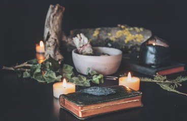 Black Kyanite crystal rock placed on top of a vintage book, among various nature items on witch's...