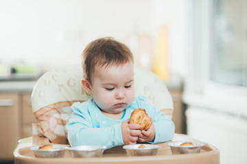 the little girl in the highchair in the hands Krapina, like muffins and croissants trend 2019