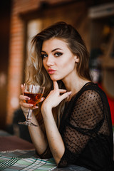 A seductive blonde holds a glass of cognac in her hand
