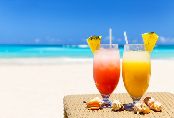 Two tropical fresh juices on white sandy beach