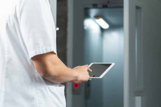 Bright Close Up Of Male Doctor In Uniform With Stethoscope And Using Computer Tablet In Hospital. Modern Medical Concept