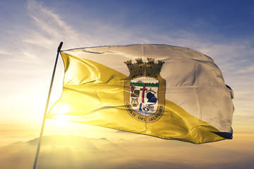 Juana Diaz municipality of Puerto Rico flag waving on the top sunrise mist fog