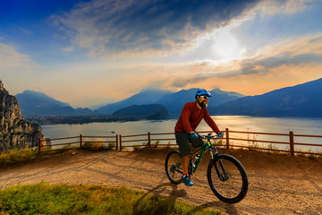 Cycling man riding on bike at sunrise mountains and Garda lake landscape. Cycling MTB enduro flow sentiero ponale trail track. Outdoor sport activity.