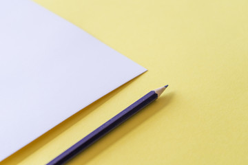 Purplepencil and white piece of paper on yellow  background. Art, scool or office shoot