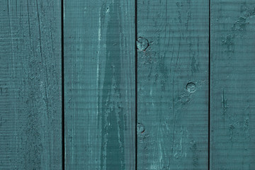 Gray-blue wooden fence rough wood. Wooden fence cracked paint. Rough wooden boards painted gray-blue. Wood texture background, oak wood wall fence. Gray and blue wood texture background.  