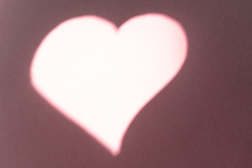 Fototapeta premium Close-up. Background with a pink sheet of paper with a heart made of shadow and light
