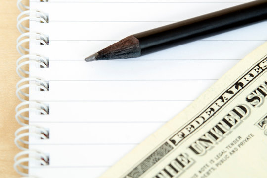 Notepad pencil money on wooden background