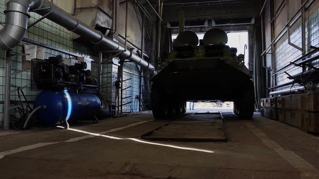 Army infantry fighting vehicle drives into the repair box. The camera is in motion.