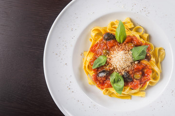 Tasty italian pasta with tomato, olive, and basil