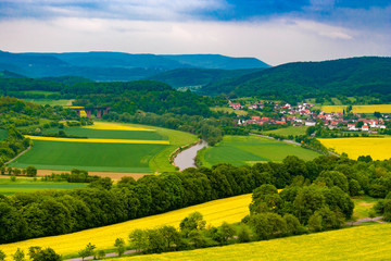 A great landscape view of the Werra Valley with the river Werra, cultivated fields, a railway bridge and the town Oberrieden; surrounded by forest and the low-mountain range of Hesse and Thuringia. - obrazy, fototapety, plakaty