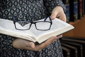 glasses on the book in the hands of women