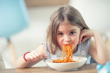 Poster Schattig klein meisje dat thuis spaghetti bolognese eet © weyo