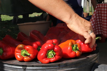 Female hand turning fresh red peppers on the outdoor stove
