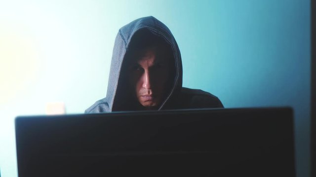 man hacker in the hood concept. unknown hacker criminal breaks into computer protection on the Internet passwords. male lifestyle hacker penetrates into hack network protection web phishing technology