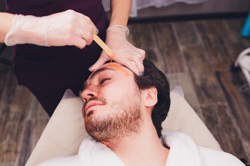 Hair removal. Man's face sugaring epilations beard trimming, yellow color, in cosmetology on the...