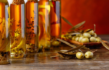 Green olives and bottles of olive oil with spices and herbs .