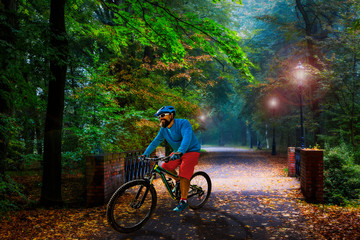 Cycling in golden shine trail foggy scene in the park, man riding on bike the morning sun shining through the trees, blue sky in background.