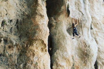 Girl rock climber climbs difficult route on the cliffs