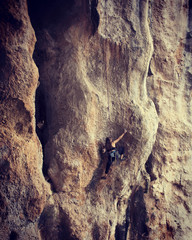 Girl rock climber climbs difficult route on the cliffs