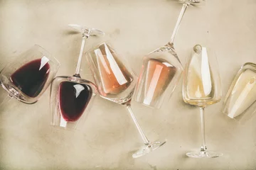  Flat-lay van rode, rose en witte wijn in glazen over grijze betonnen achtergrond, bovenaanzicht. Wijnbar, wijnmakerij, wijndegustatieconcept © sonyakamoz