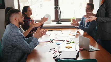 Business concept. A working team at the conference. A woman draw something on the paper and the team clapping their hands