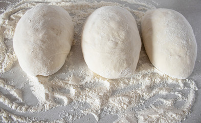 Pieces of dough on a white table with flour.
