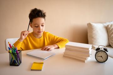 Thinking child bored, frustrated and fed up doing his homework