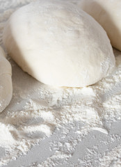 Pieces of dough on a white table with flour.
