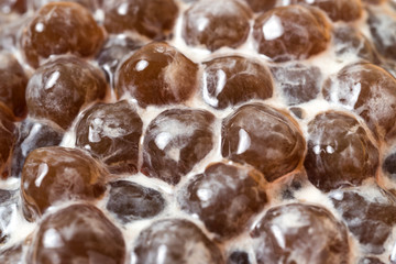 A glass cup of pearl milk tea (also called bubble tea) and a plate of tapioca ball on wooden background. Pearl milk tea is the most representative drink in Taiwan. Taiwan food . With copy space.